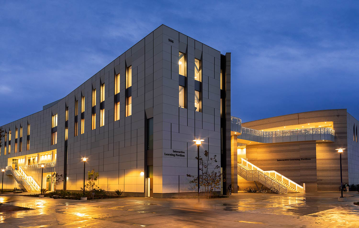 photo of ILP building at night with amber colored lights illuminated in the windows and on the stairwell